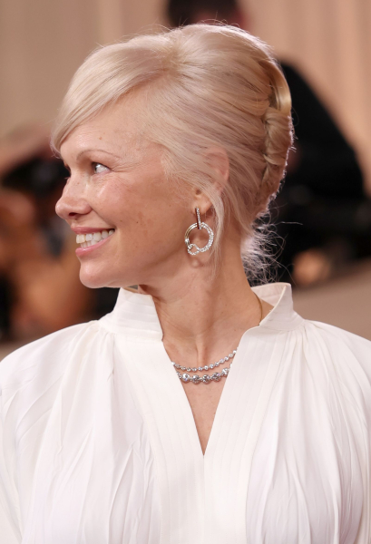 Pamela Anderson smiling in profile in a white blouse